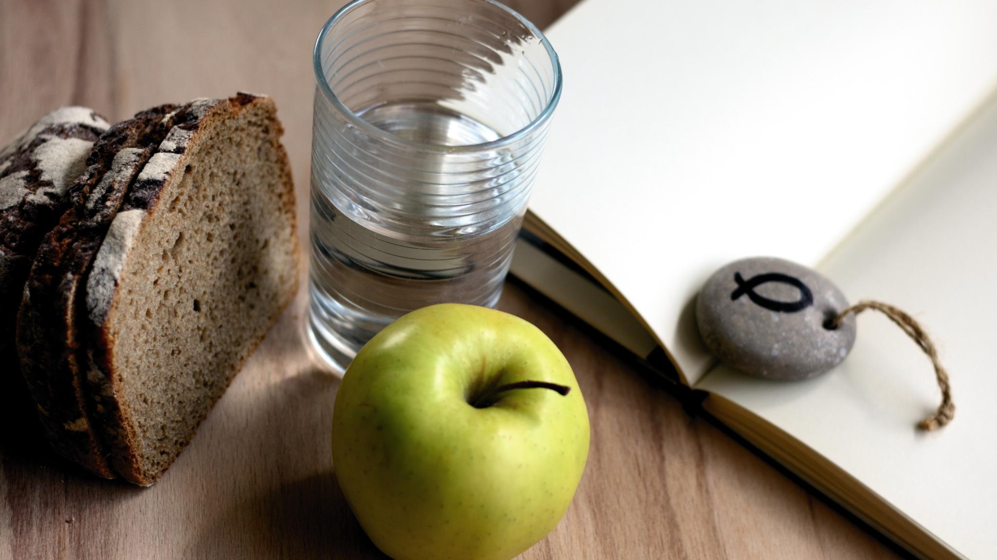 Brot, Apfel, Glas Wasser und ein Stein